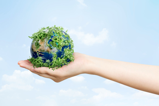 A human hand gently holding a small Earth, which is partially covered in lush green foliage as National Composites Centre: Sustainable Carbon Fibre Innovation