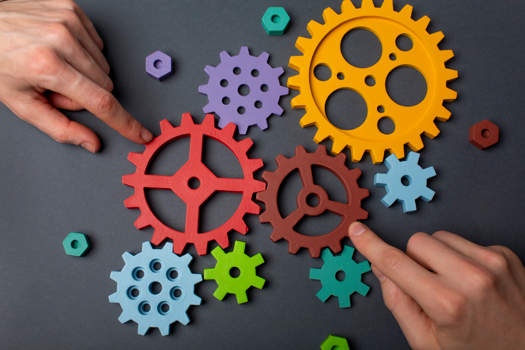 Creds: FreePik - Hands assembling colorful gears in a skills competition setup.